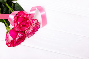 Beautiful roses and red ribbon on white background. The concept of the holidays