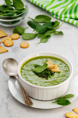 Creamy green spinach soup in a white bowl, spring healthy green creamy soup. Detox, dieting or clean eating food.