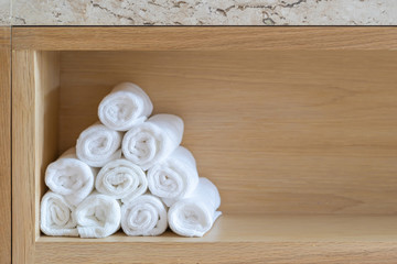 Obraz na płótnie Canvas Towels white soft cotton neatly folded clothes on wooden cabinet wall built in the bathroom clean textile, concept interior for spa and hygiene