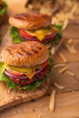 Hamburgers and burgers with french fries on a wooden texture, vertical frame