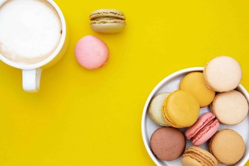 Cup of coffee and macaroons on colorfu lyellow background. top view. Copy space.