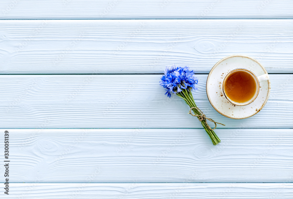 Poster Summer tea party. Cup near cornflowers bouquet on blue wooden background top-down copy space