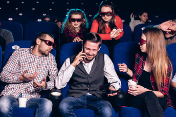 The guy speaks on the phone and interferes with watching a movie in a movie theater. Stock photo of...