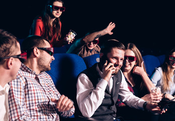 The guy speaks on the phone and interferes with watching a movie in a movie theater. Stock photo of...