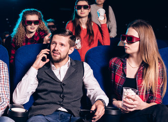 The guy speaks on the phone and interferes with watching a movie in a movie theater. Stock photo of...