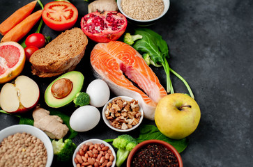 Selection of healthy food: salmon, fruits, seeds, cereals, superfoods, vegetables, leafy vegetables on a stone background   with copy space for your text.Healthy food for people 