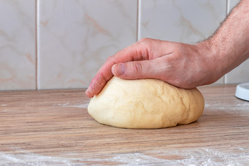 Hands kneading dough. Man kneading dough on the table by hand in domestic kitchen