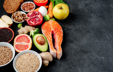 Selection of healthy food: salmon, fruits, seeds, cereals, superfoods, vegetables, leafy vegetables on a stone background   with copy space for your text.Healthy food for people 