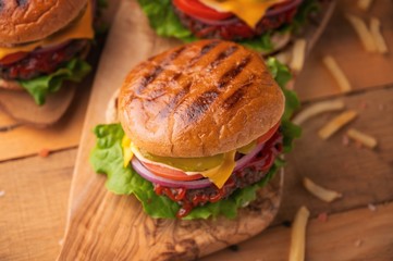Juicy burgers on a wooden background with french fries. Home recipes, or cafe. Calorie and junk food.