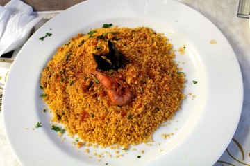 fish couscous with a mussel and a shrimp served on a round white plate