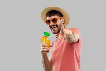 summer, vacation and people concept - happy smiling young man in sunglasses and straw hat with orange juice cocktail