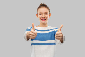 gesture and people concept - smiling teenage girl in pullover showing thumbs up over grey background