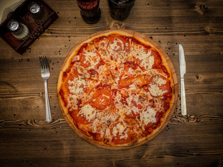 Delicious delicious pizza on a table with a ragged surface in a cafe. Hot fresh pizza