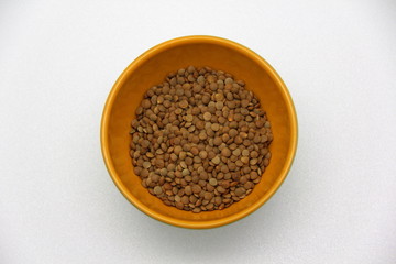 Ceramic bowl with lentils on a white background, top view