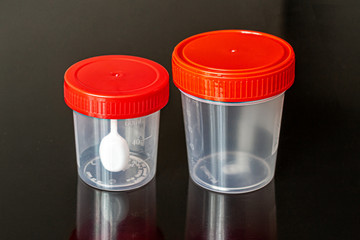 Two transparent plastic containers with red lids on a dark background