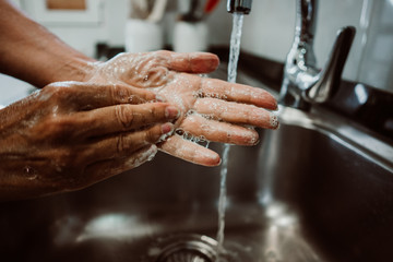 Middle-aged woman washing her hands with soap and water to avoid contagion of the coronavirus. Health risk prevention in old population. Healthcare