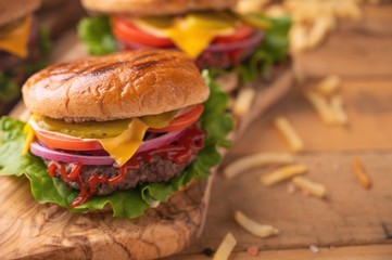 Juicy burgers on a wooden background with french fries. Home recipes, or cafe. Calorie and junk food.