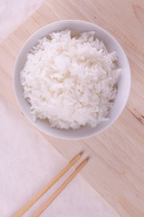 White rice on ceramic plate top view with bamboo chopstick