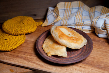 Clay plate of fried meat pies on wooden table.