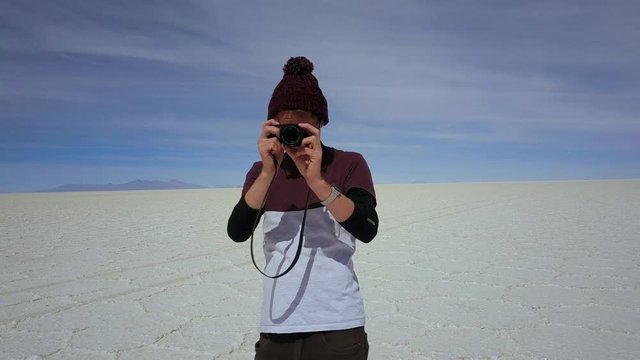 Young traveler taking photo at the Uyuni Salt Flat, Bolivia - aerial tracking away
