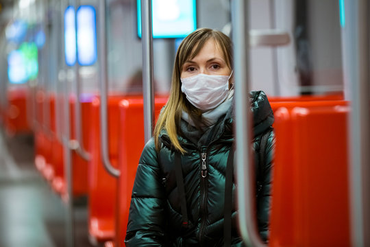 Woman in winter coat with protective mask on face sitting in subway car, using phone, looking worried. Preventive measures in public places of epidemic regions. Finland, Espoo - Powered by Adobe