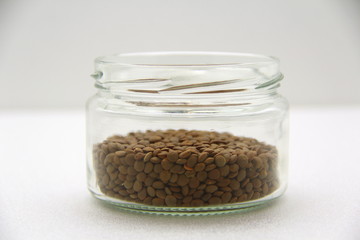 Glass jar with lentils on a white background, side view.