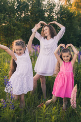 Fototapeta premium Woman and two girls together in a field with lupins