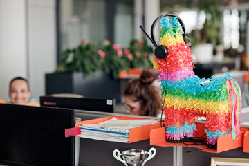 Donkey pinata in openspace office wearing callcenter headphones