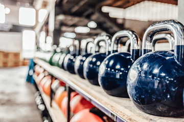 Kettlebells with various colors. Sport equipment in gym. kettlebell on floor background, Fitness training. Shot of a bunch of kettle bells lined up in a row on the floor of a gym