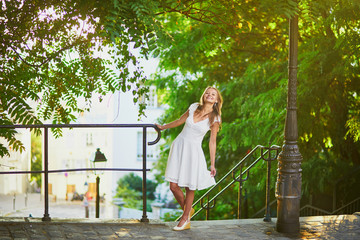 Woman in white dress walking on famous Montmartre hill in Paris, France at early morning