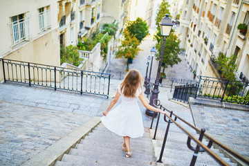 Woman in white dress walking on famous Montmartre hill in Paris, France at early morning