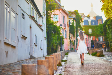 Fototapeta na wymiar Woman in white dress walking on famous Montmartre hill in Paris, France at early morning