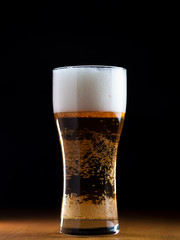 A glass of lager light beer on a wooden table