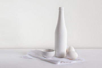 Still life of a bottle of eggs and towels on a white background.