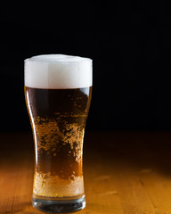 A glass of lager light beer on a wooden table