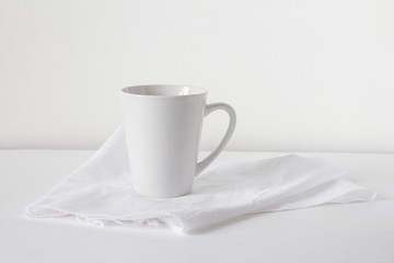 White coffee mug on a towel stands on a light background.