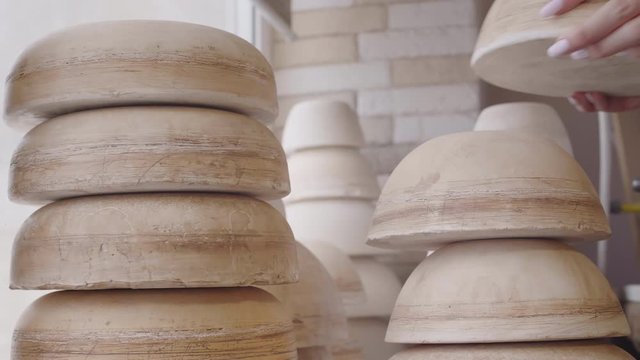 Close up of clay billets of different shape lying on table in workshop and unrecognizable female hand taking one of them