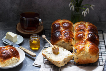 Traditional hot cross buns with honey and butter on a concrete background.