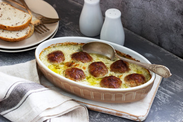 Baked meatballs in a creamy sauce and slices of bread with flax on a concrete background.