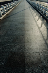 A long marble tile road with white metal railings with a vanishing line on the horizon, empty with nobody, concept of direction alone.