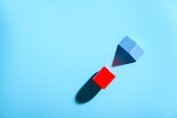 Two small pieces of wood isolated on plain blue background with hard shadows.