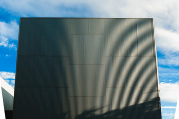 High building of corrugated aluminum plates, flat against the blue sky.