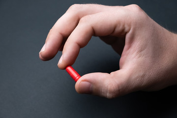 Мan's hand with medicine on a black background. Treatment of a coronavirus, flu , or cold. Medical concept