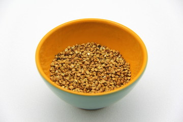 Ceramic bowl with buckwheat on a white background, top view