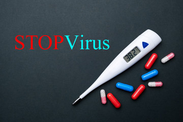 Obraz premium Thermometer and medication on a black background. Treatment of a coronavirus, flu , or cold. Medical concep