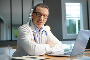 Doctor in office working on laptop