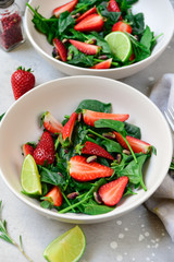 Fitness food spinach and strawberry salad in white bowls on a light table. food delivery of diet dishes. dish for spring and summer menu business lunch. the view from the top. selective focus
