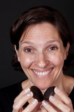 Older Woman Eating A Chocolate Cream Filled Cookie.