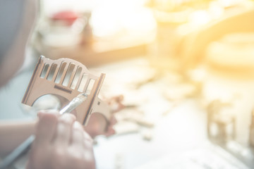 child with a brush paints a wooden crib at the table in sunny weather