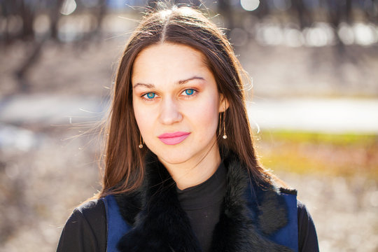 Portrait of a young beautiful woman in blue coat in spring park